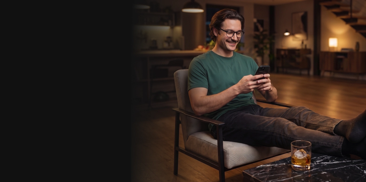 Hombre sonriendo en su living mirando el celular